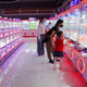 People play physical claw machine games in a mall.